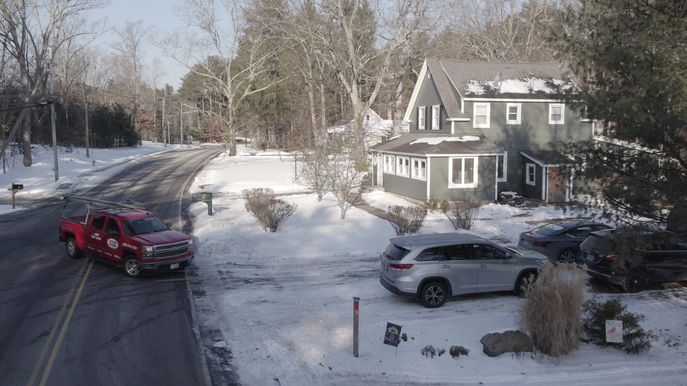 Drone view across a snowy residential street