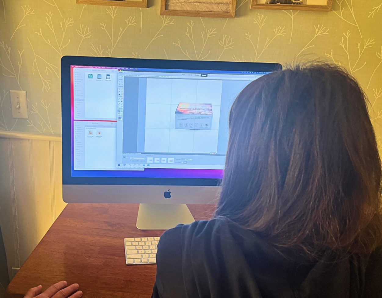 Person seated at iMac editing on screen