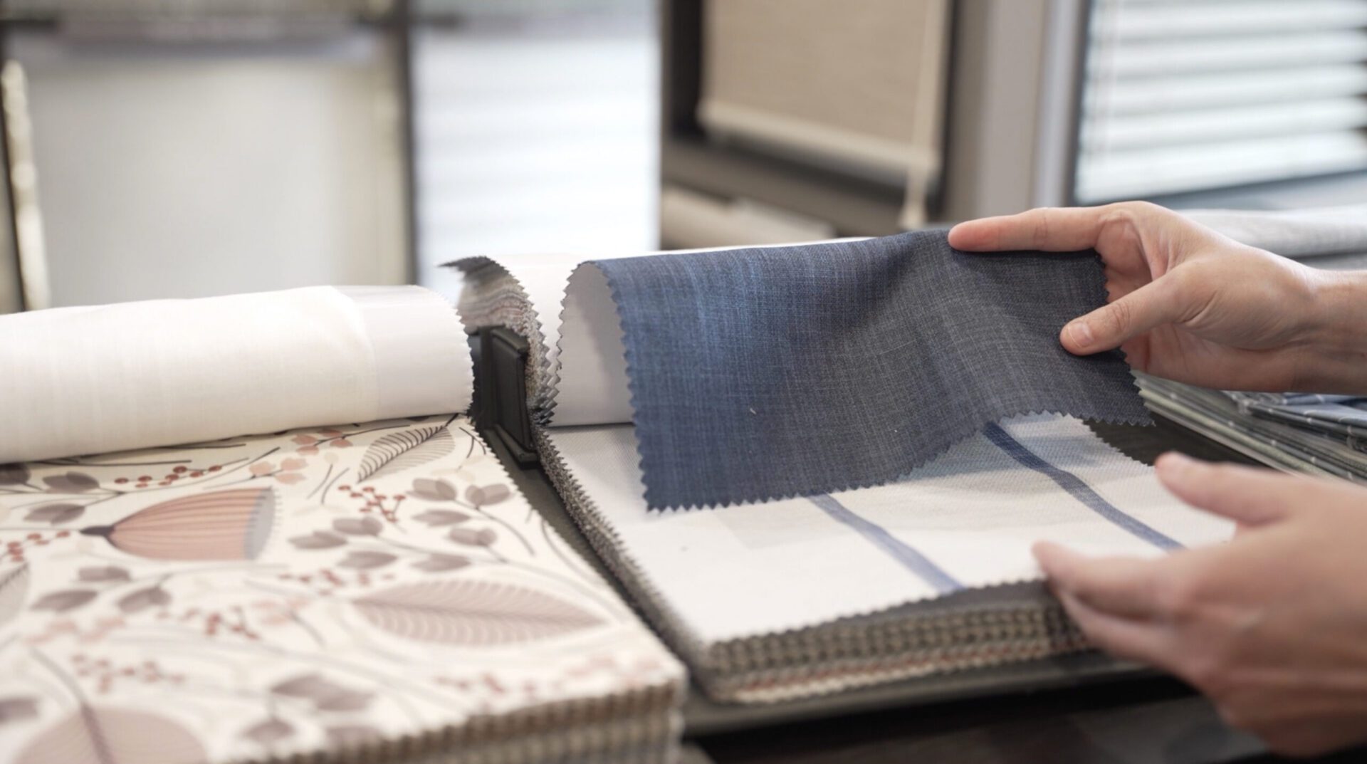 Hands selecting fabric samples from catalog.