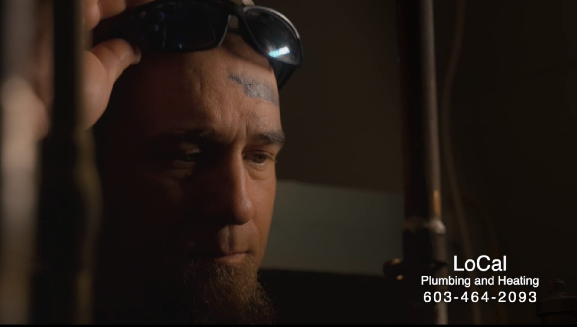 Plumber examining pipes in dim light