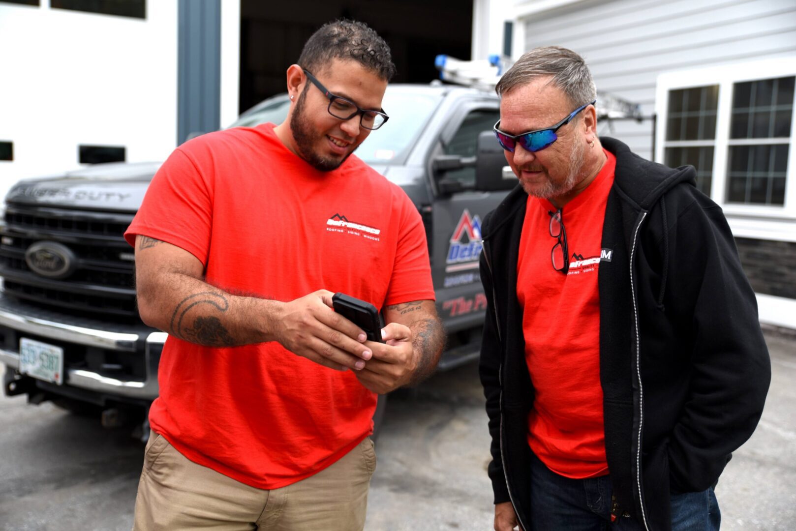 Two men in red shirts with smartphone.