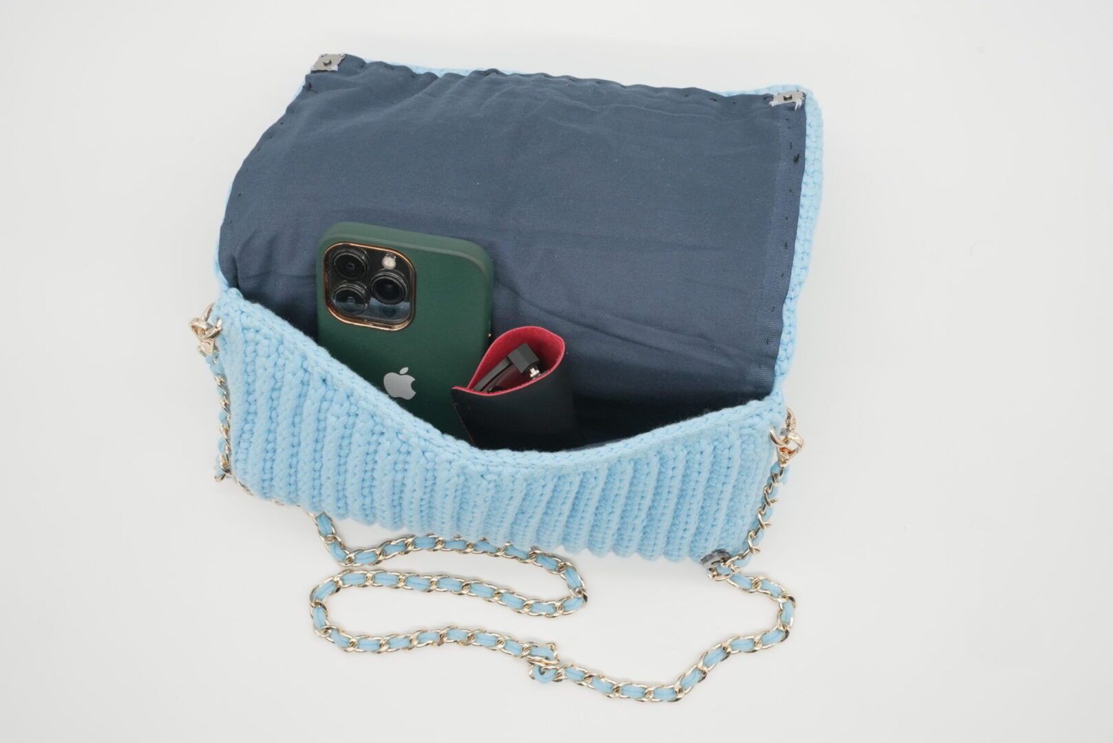 Open blue handbag with phone and lipstick.