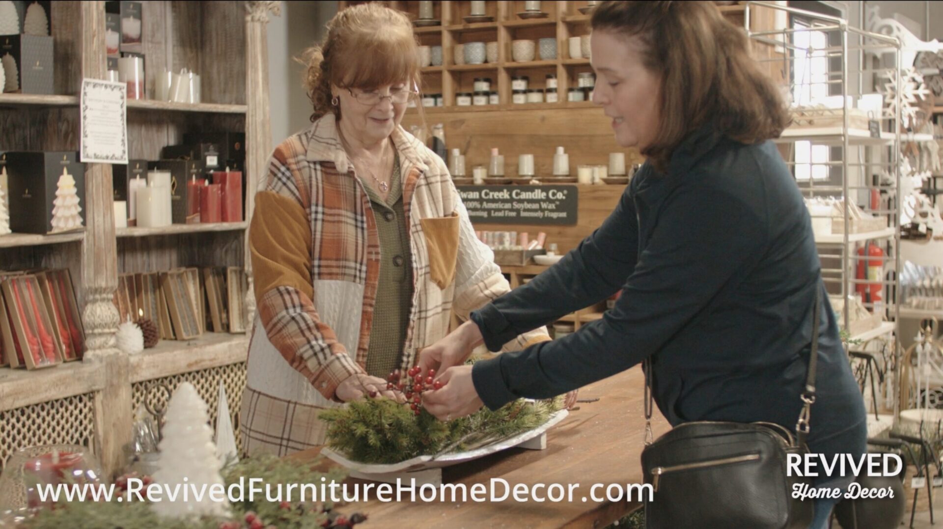 Women arranging decorative greenery in store.