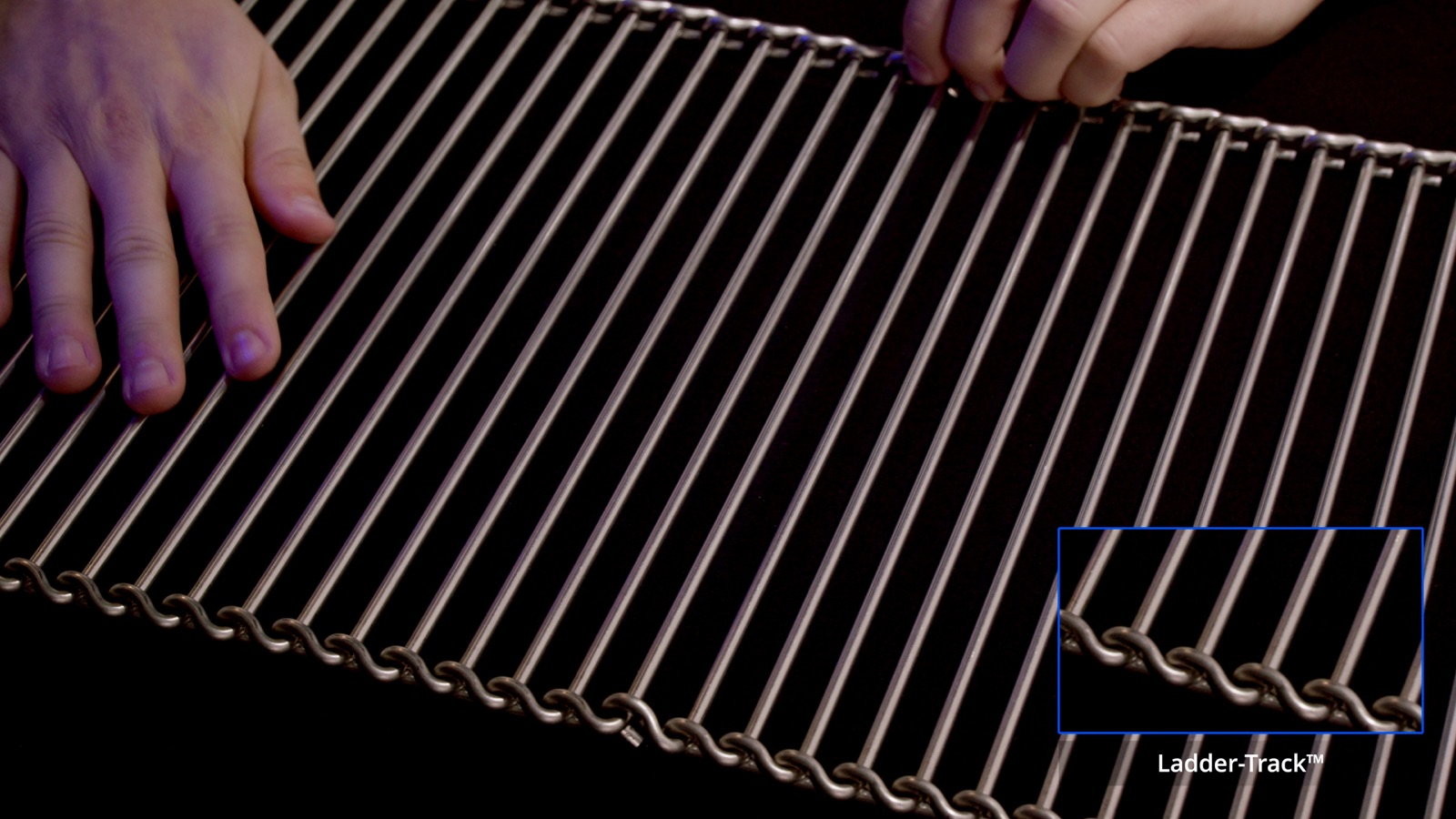 Hands positioning an open wire belt section — Wire Belt Company of America