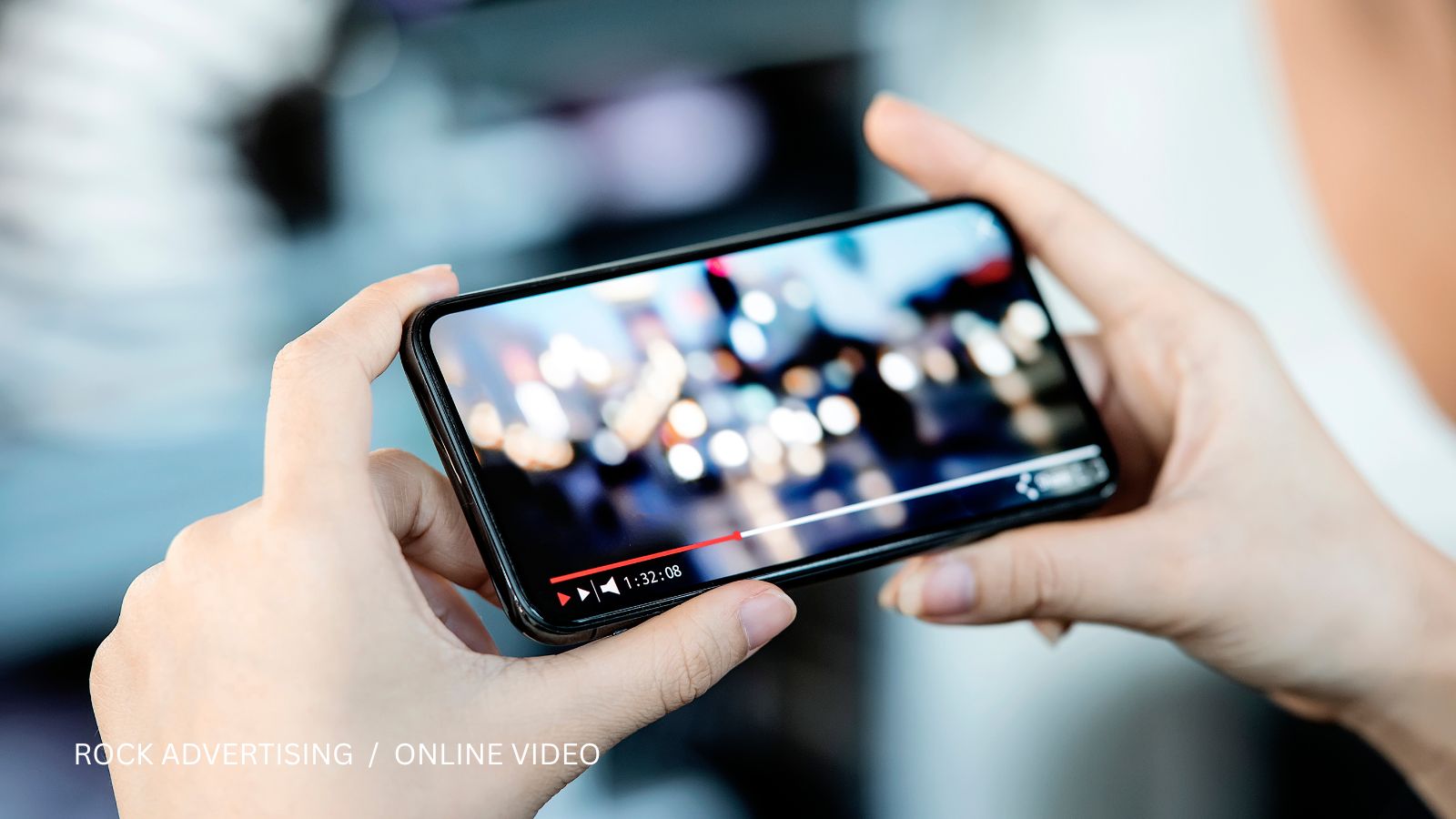 Hands holding a smartphone horizontally while watching online video